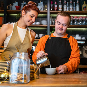 Happy young man with developmental disabilities working in a cafe